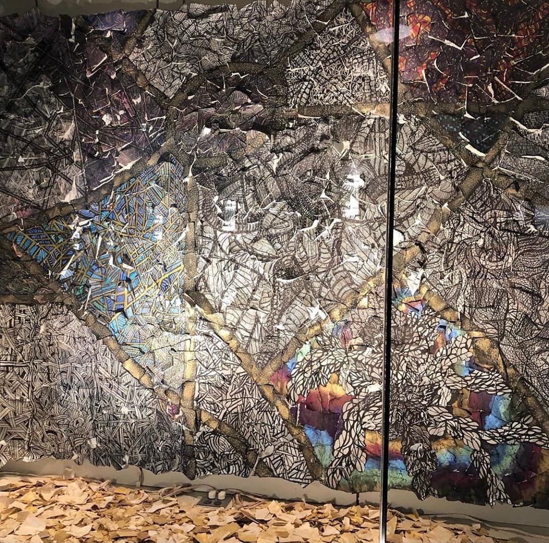 Video Mixed media sculptural figure by Cheyenne Sandoval featuring black feathers, beaded hood, and abstract blue and red patterning